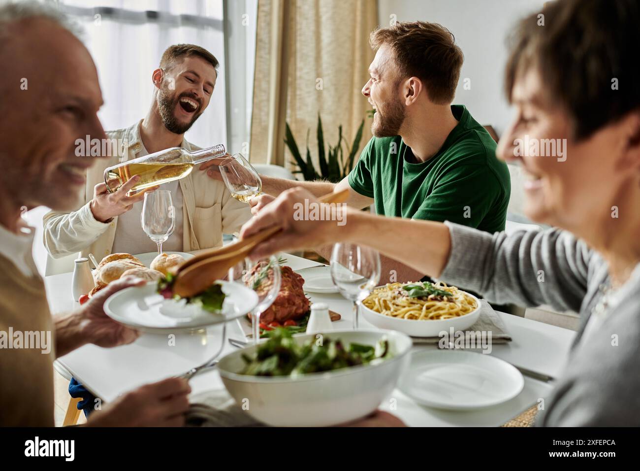 Un couple gay aime un repas en famille, partageant des rires et des bons moments. Banque D'Images