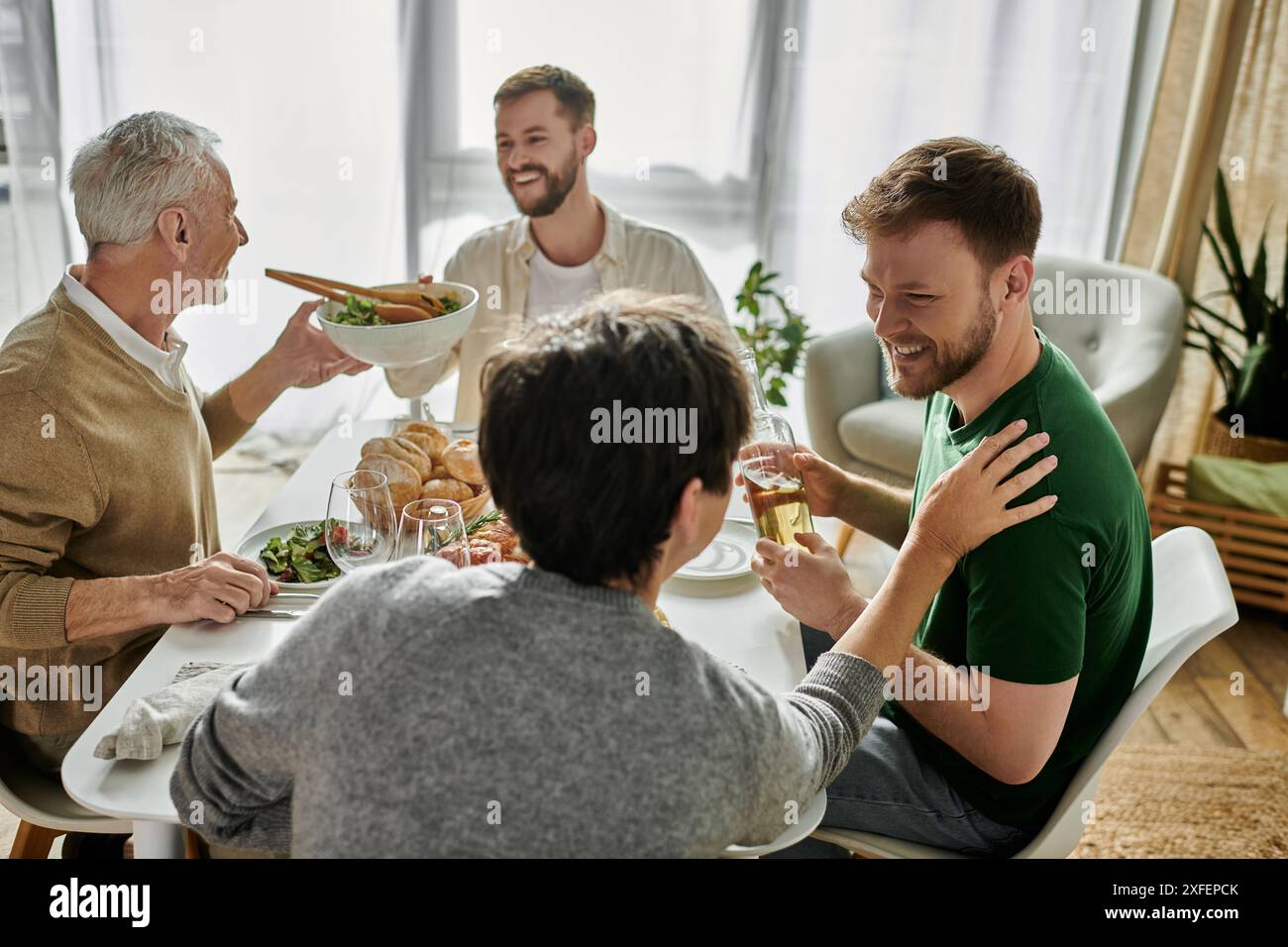 Un couple gay aime un repas avec les parents à leur domicile. Banque D'Images