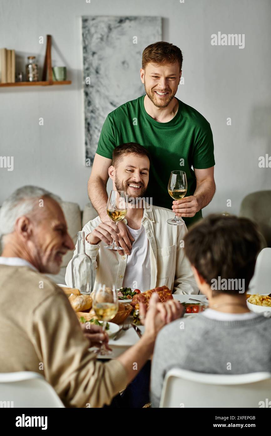 Un couple gay et sa famille profitent d'un repas ensemble à la maison. Banque D'Images