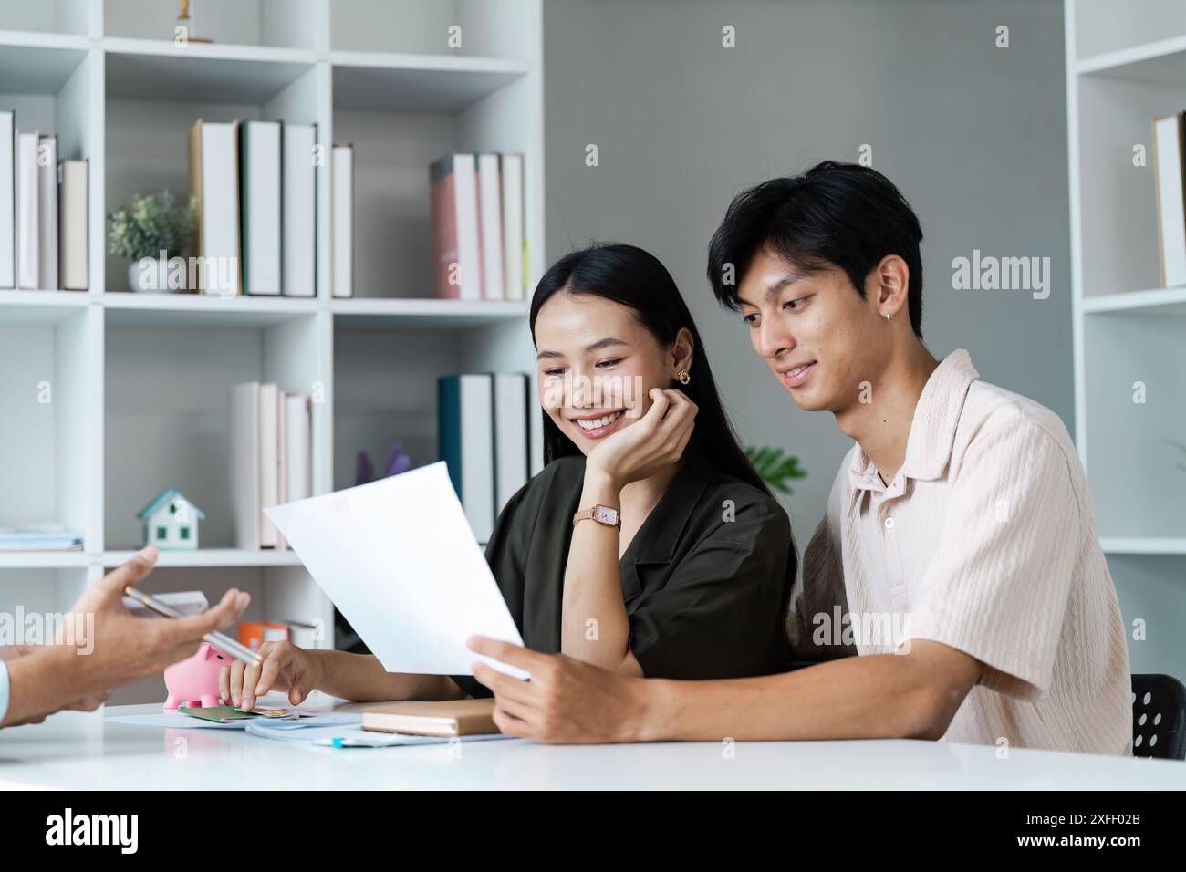 Un couple joyeux est assis à une table, examinant les documents financiers et planifiant leur avenir ensemble dans un cadre moderne. Banque D'Images