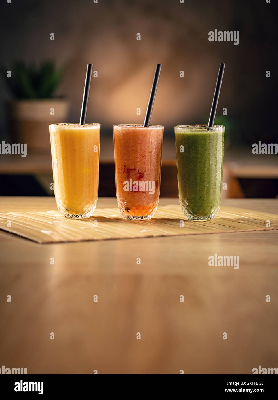 Trois smoothies colorés debout sur une table en bois Banque D'Images