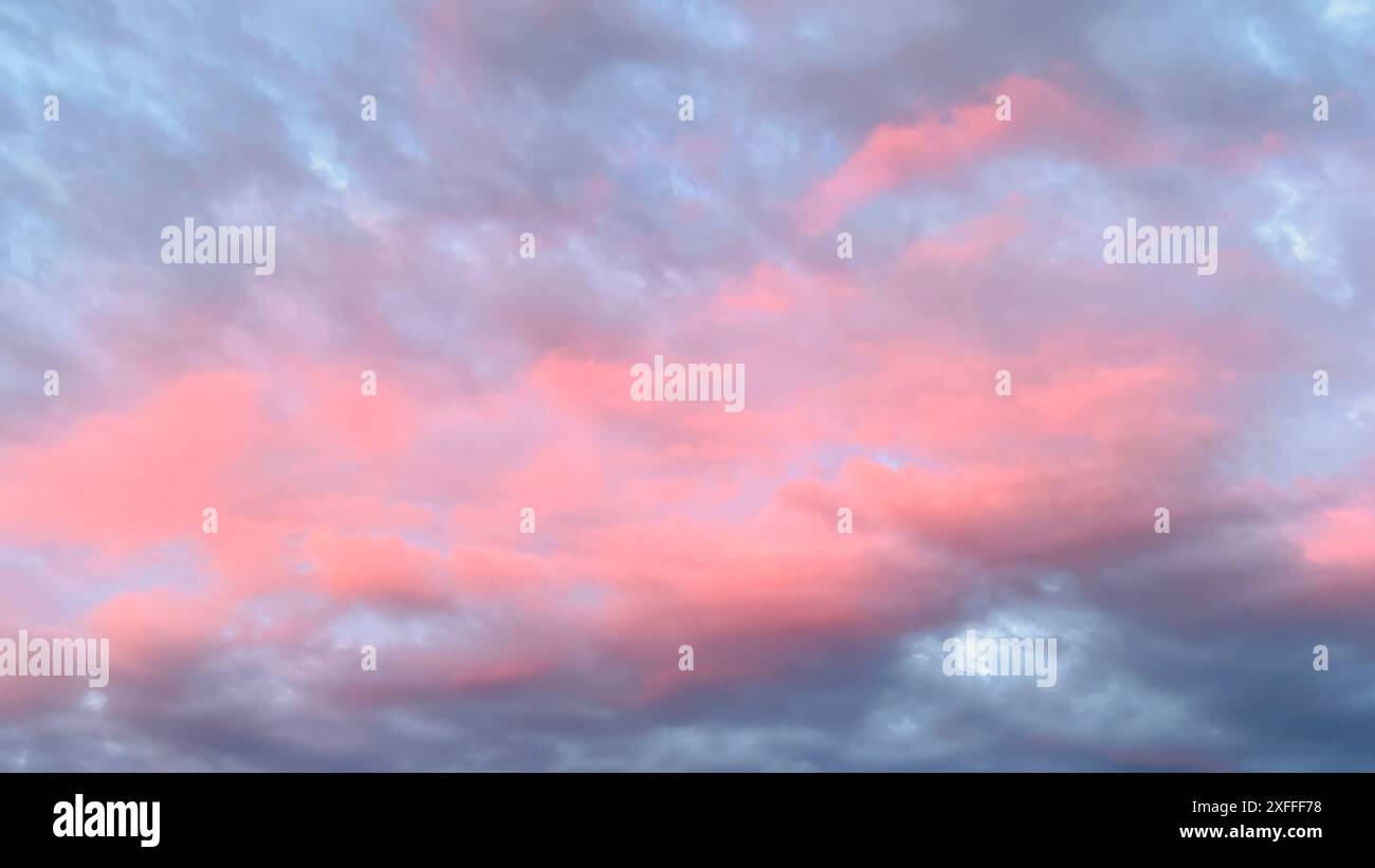 Twilight Cloudscape : des teintes roses douces se répandent dans le ciel et se mélangent avec des nuances de bleu et de gris. Les nuages suggèrent la paix, la sérénité et le calme. Banque D'Images