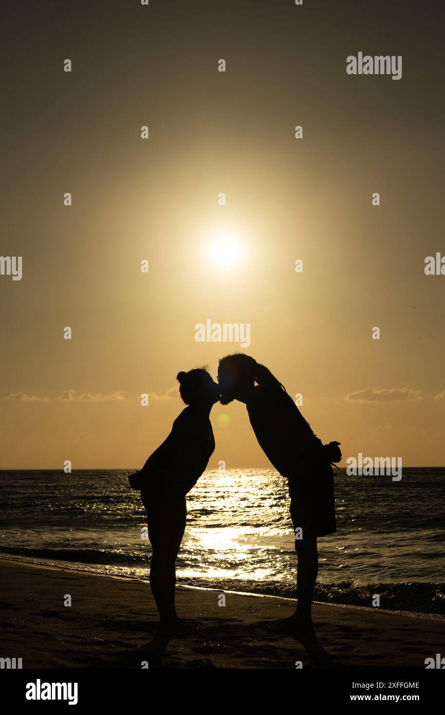 Photo d'un couple marié s'embrassant contre la lumière avec le soleil en arrière-plan sur un coucher de soleil sur la plage des Caraïbes à Varadero Cuba Banque D'Images