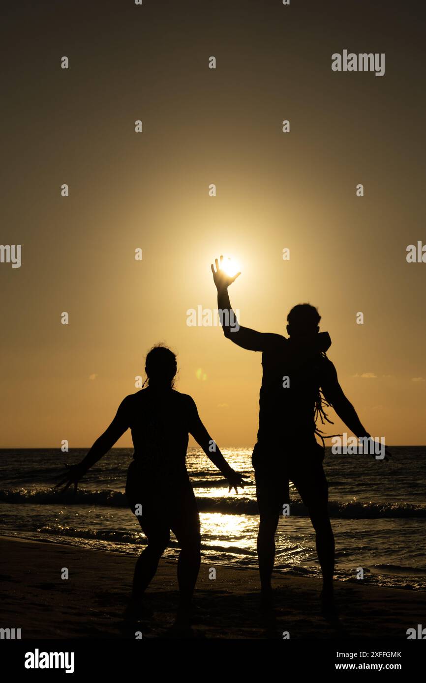 Photo d'un couple marié sautant contre la lumière avec le soleil en arrière-plan sur un coucher de soleil sur la plage des Caraïbes à Varadero Cuba Banque D'Images