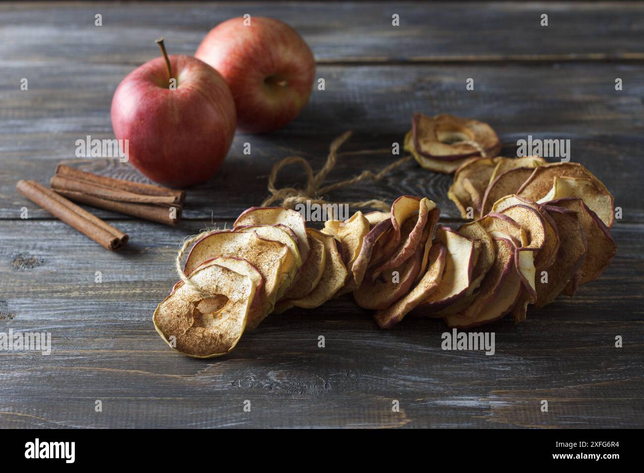 Pommes séchées maison à la cannelle, chips de pomme sur fond en bois. Délicieux en-cas sain Banque D'Images