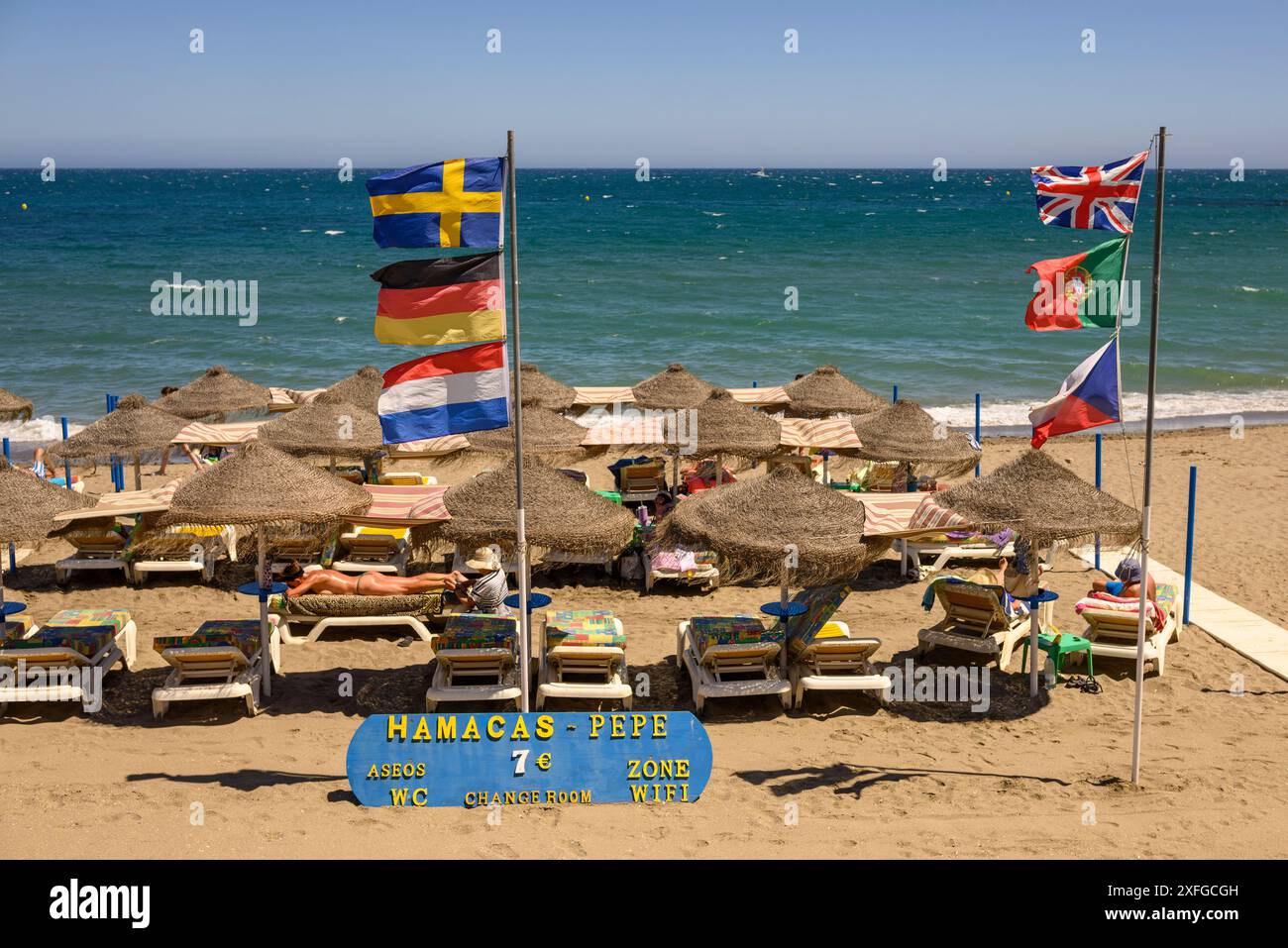 Femme recevant un massage corporel sur la plage de Benalmadena, Costa del sol, Espagne avec des drapeaux soufflant dans le vent fort Banque D'Images