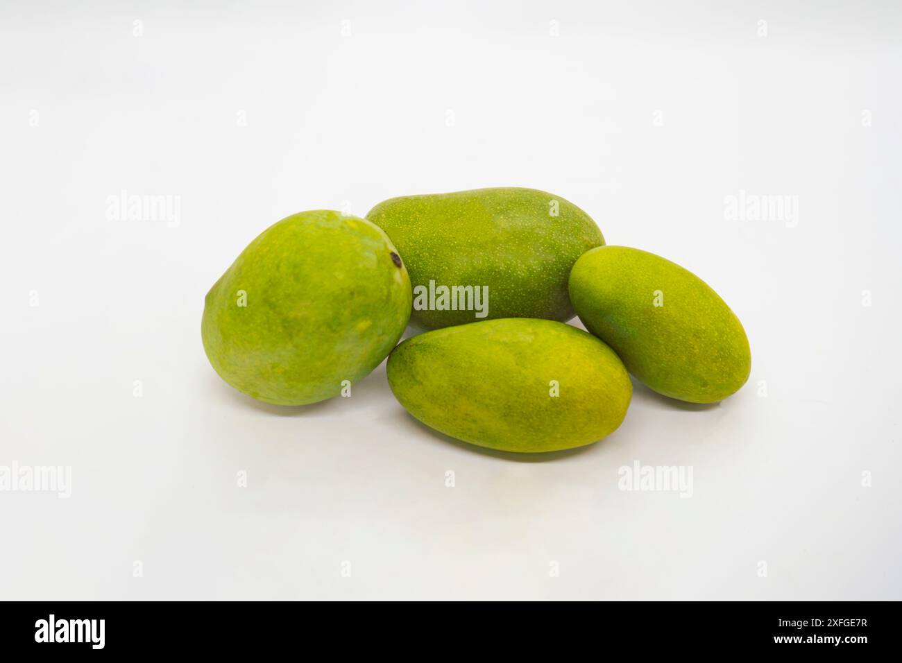 Délicieuse mangues vertes hachées fruits tropicaux coupés tranches et entiers dans un panier fond blanc isolé Banque D'Images