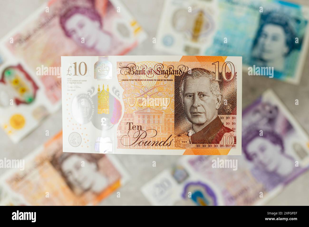 Nouvelle monnaie britannique avec le roi Charles III, émise pour la première fois en juin 2024 par la Banque d'Angleterre, Royaume-Uni. En arrière-plan, les billets de banque plus anciens avec l'image du Banque D'Images