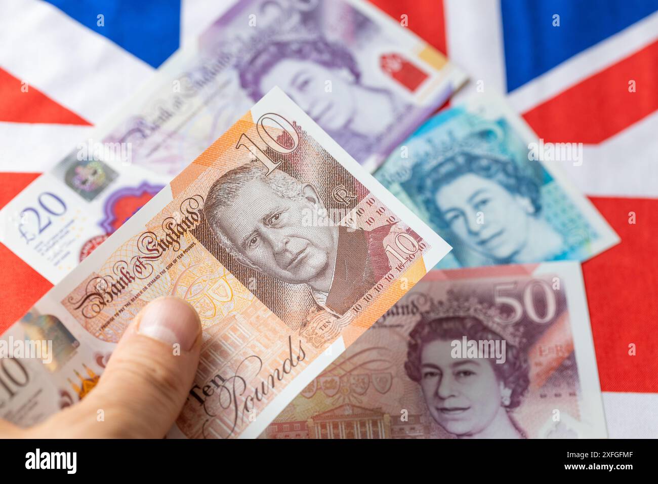 Nouvelle monnaie britannique avec le roi Charles III, émise pour la première fois en juin 2024 par la Banque d'Angleterre, Royaume-Uni. En arrière-plan, drapeau et billets plus anciens avec l'ima Banque D'Images