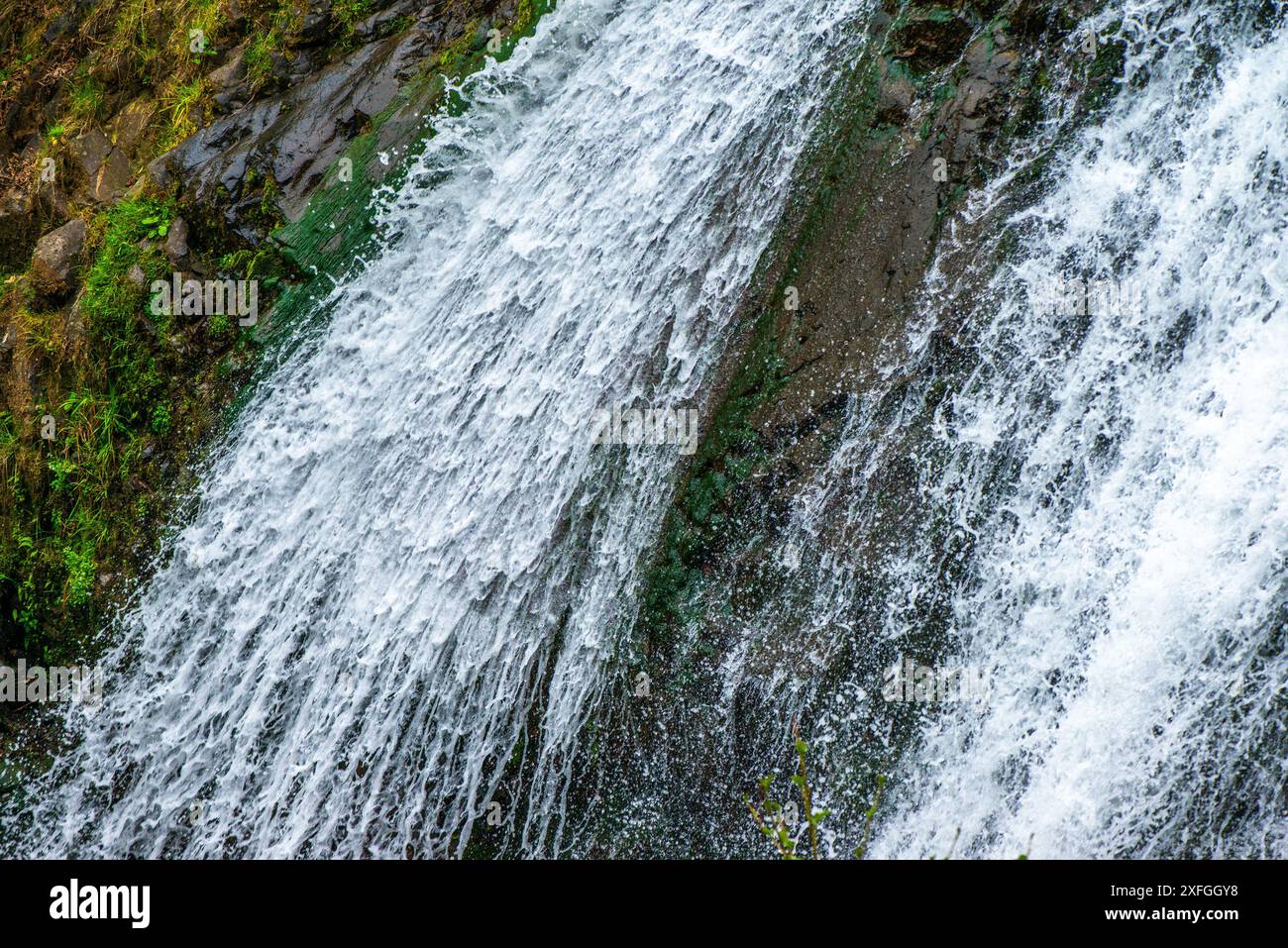 Une captivante photo en gros plan d'une cascade, mettant en valeur l'écoulement dynamique et les détails complexes des eaux en cascade. Banque D'Images