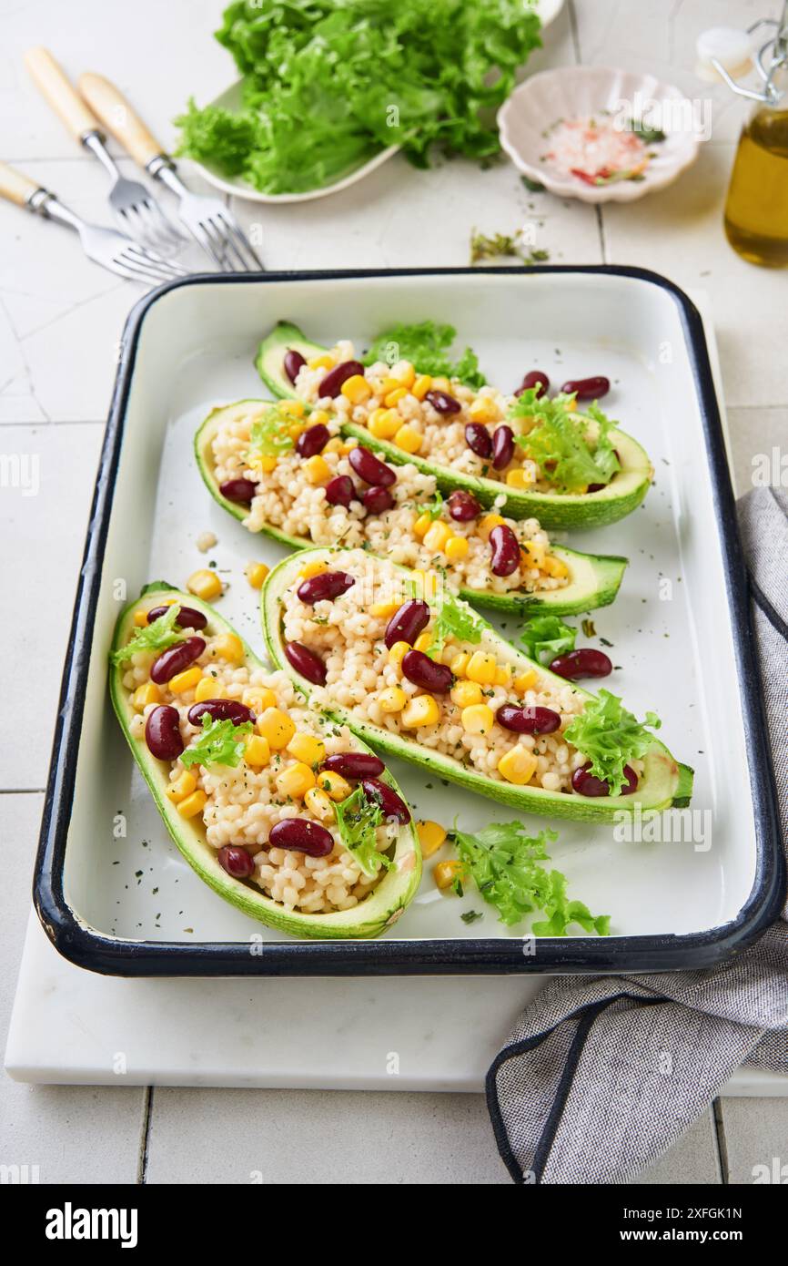 Courgettes farcies au petitim, haricots rouges, maïs au basilic et sauce cuite sur un vieux fond de tuiles craquelées. Vue de dessus. Banque D'Images