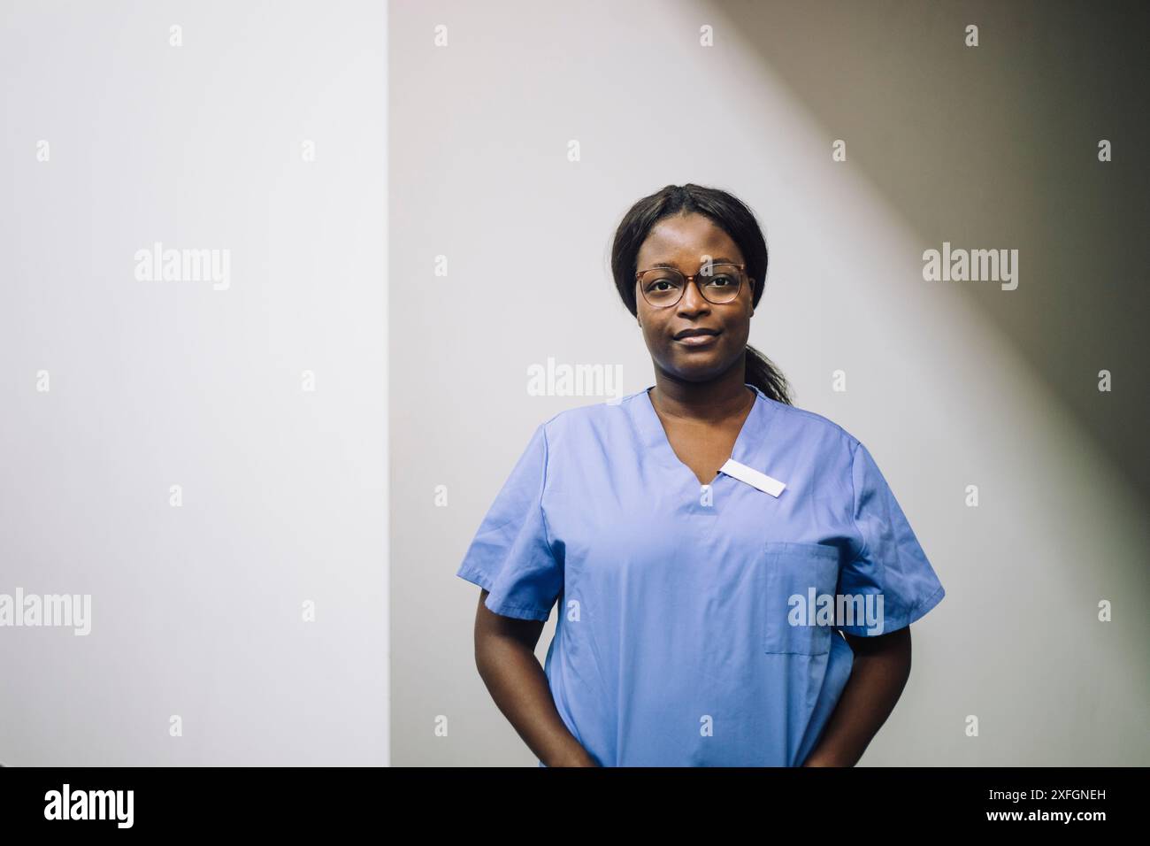 Portrait d'une praticienne confiante debout contre un mur blanc à l'hôpital Banque D'Images