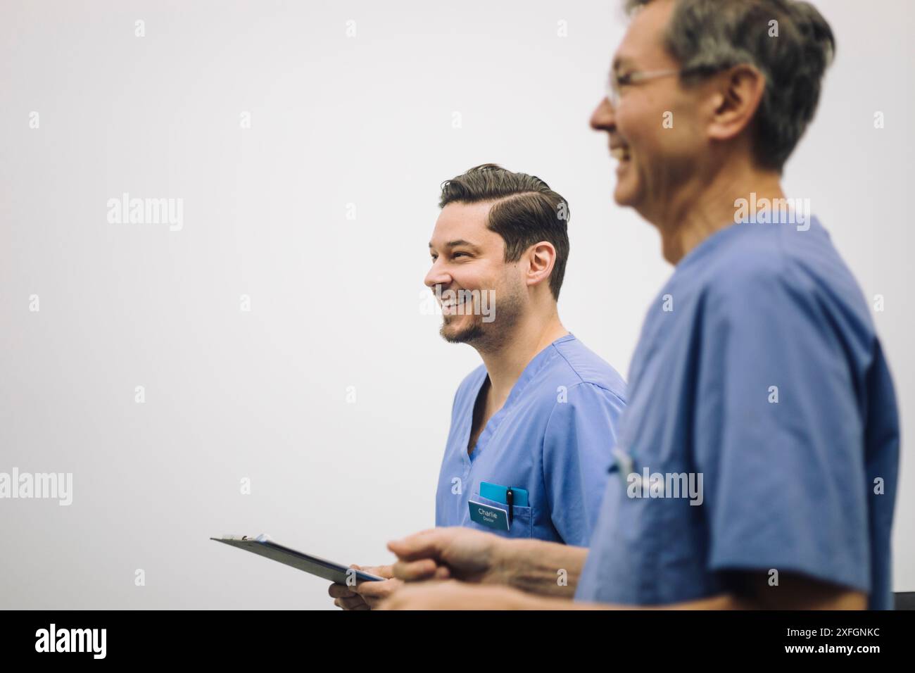 Des experts médicaux masculins souriants près du mur blanc à l'hôpital Banque D'Images