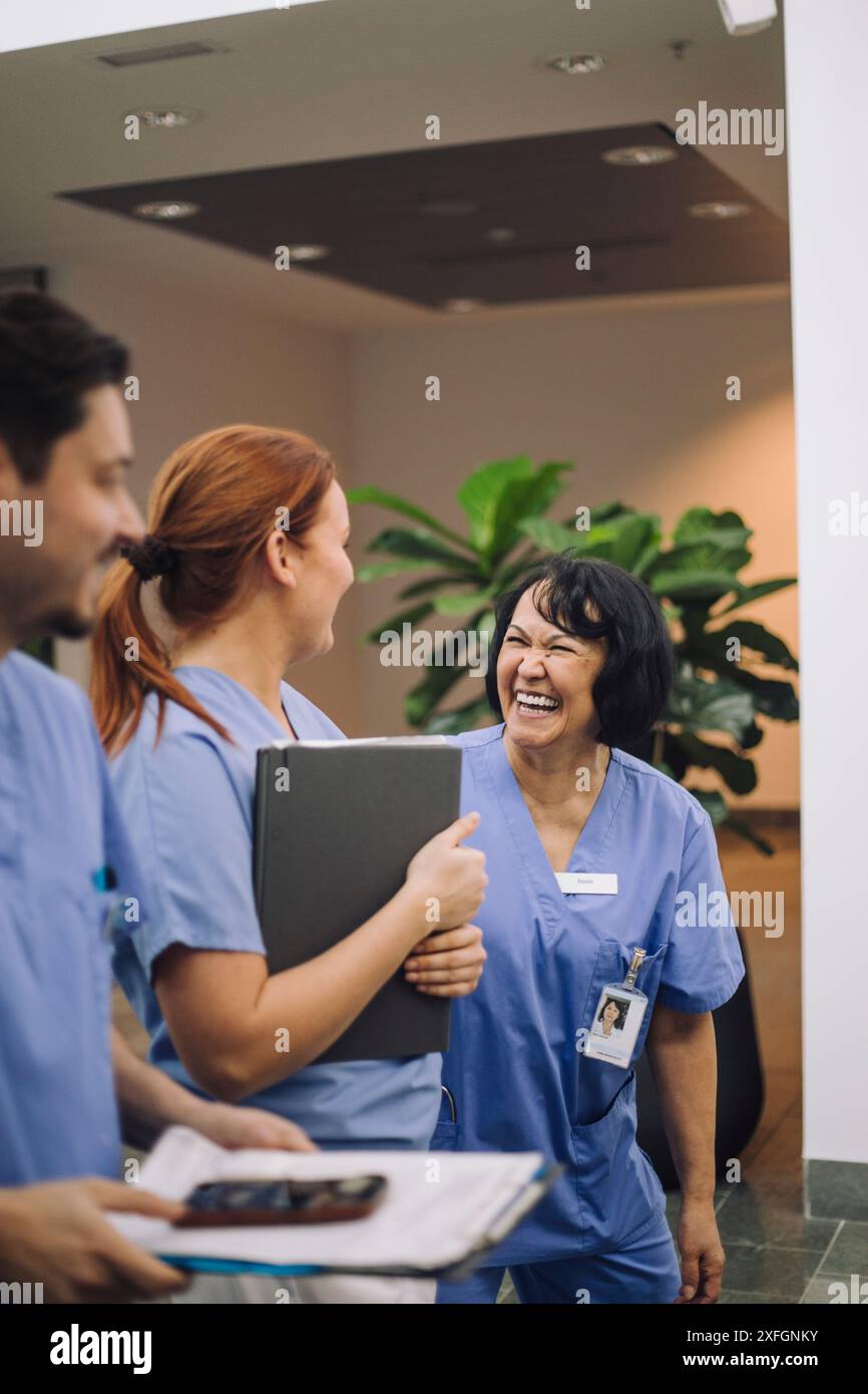 Professionnelle médicale senior riant tout en parlant avec un collègue à l'hôpital Banque D'Images