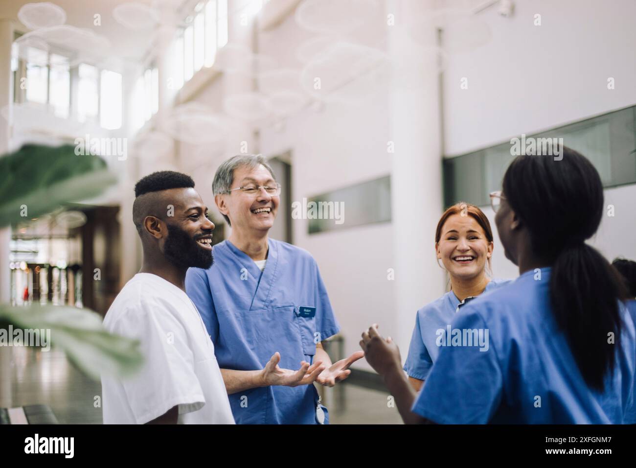 Heureux professionnels de la santé masculins et féminins appréciant tout en parlant les uns avec les autres dans le hall de l'hôpital Banque D'Images