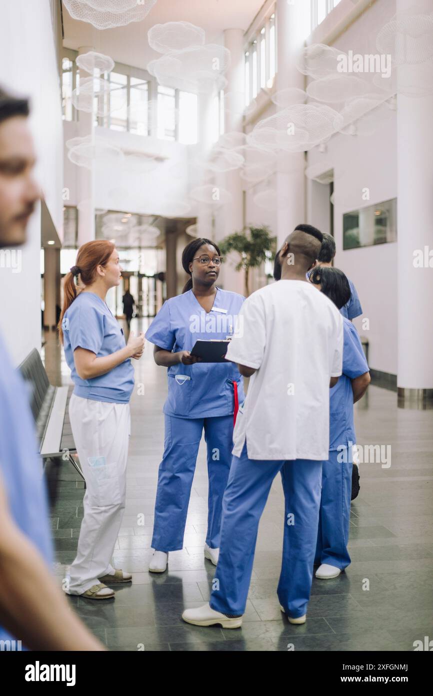 Professionnels de la santé multiraciaux masculins et féminins discutant dans le hall de l'hôpital Banque D'Images