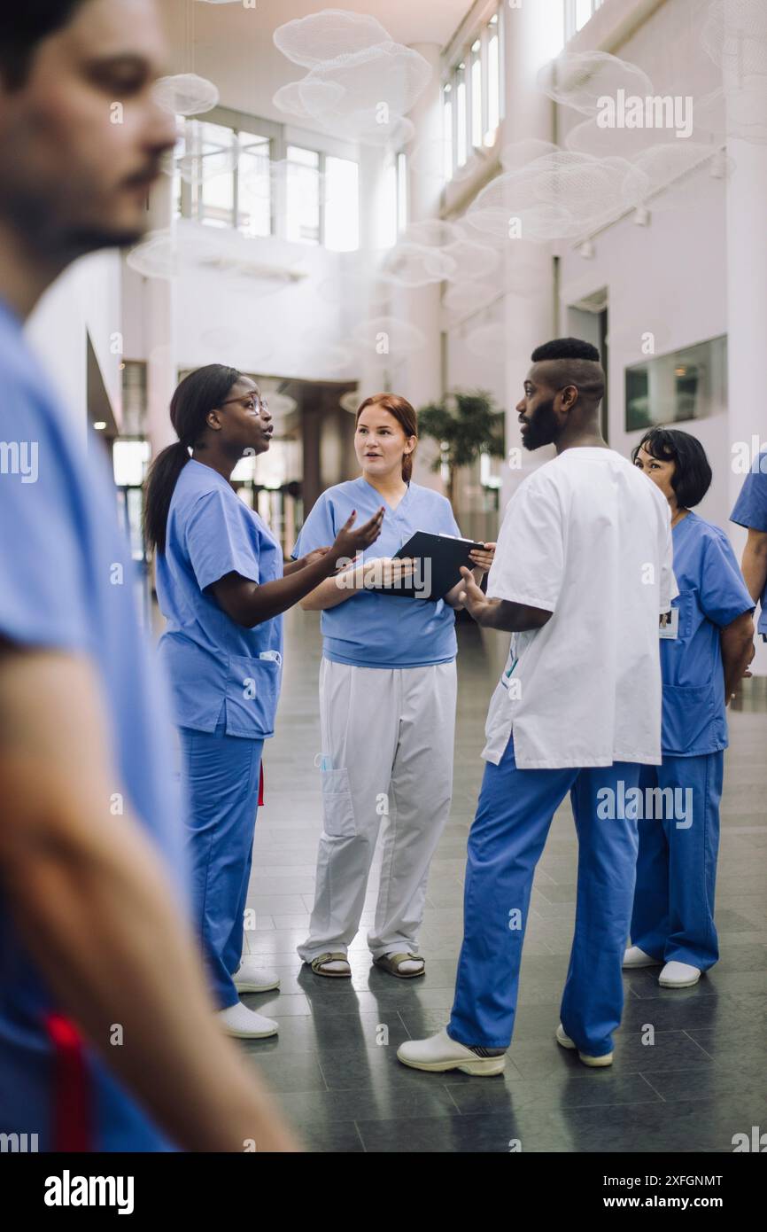 Praticienne discutant avec des collègues dans le hall de l'hôpital Banque D'Images
