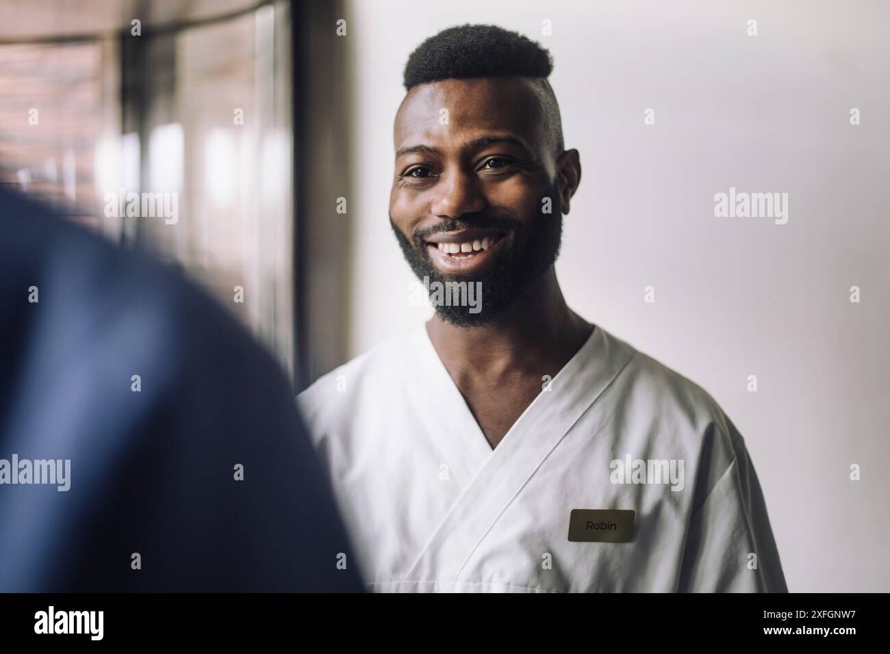 Un travailleur de santé barbu souriant en gommage à l'hôpital Banque D'Images