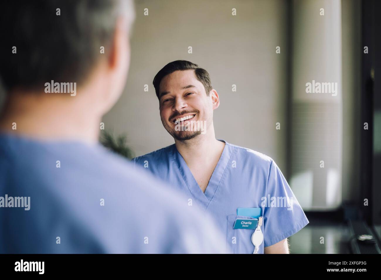 Médecin souriant parlant avec un collègue masculin senior à l'hôpital Banque D'Images