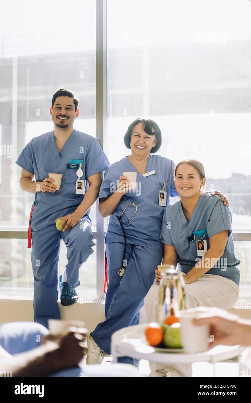 Portrait d'experts médicaux masculins et féminins souriants assis dans la cafétéria de l'hôpital Banque D'Images