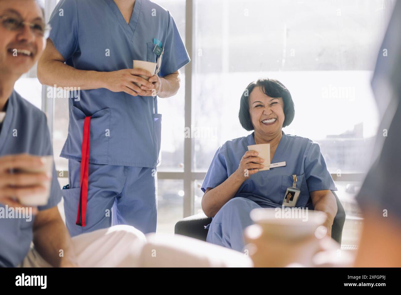 Heureuse médecin senior riant avec des collègues pendant la pause café à l'hôpital Banque D'Images