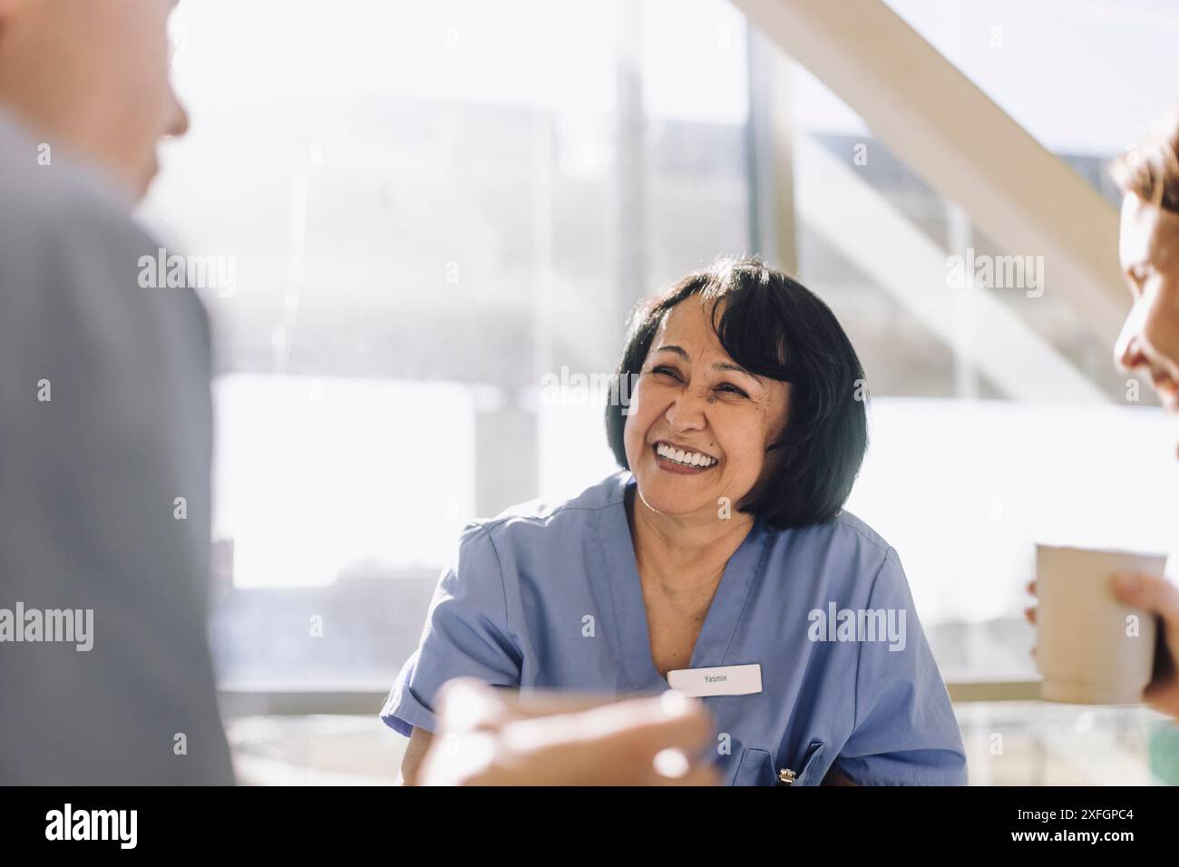 Médecin senior souriant prenant un café avec des collègues dans la cafétéria de l'hôpital Banque D'Images