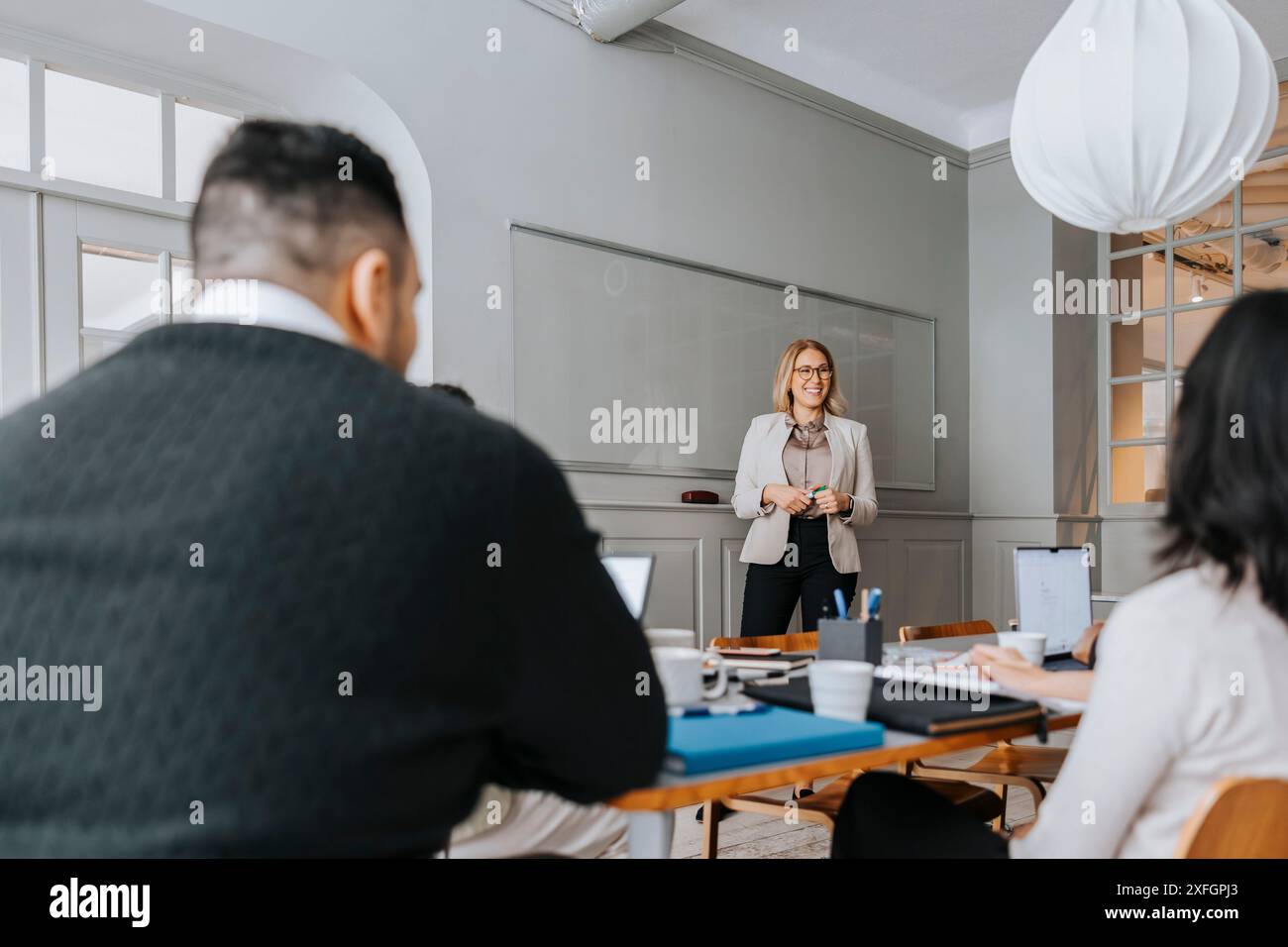 Femme d'affaires mature souriante faisant réunion d'équipe avec des collègues au bureau Banque D'Images