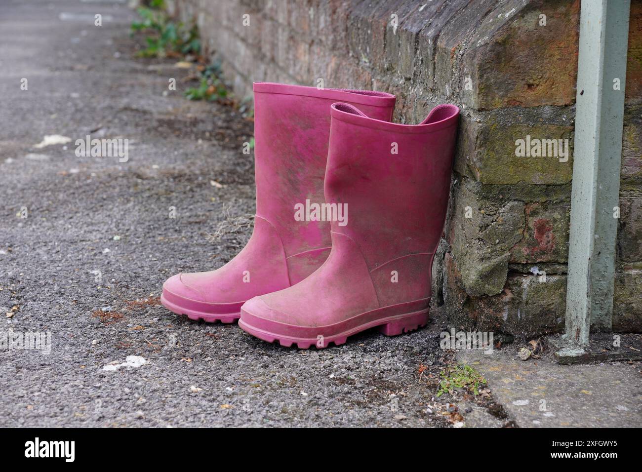 Une paire de bottes wellington pour enfants devant la porte de la maison. chaussures roses pour temps humide Banque D'Images