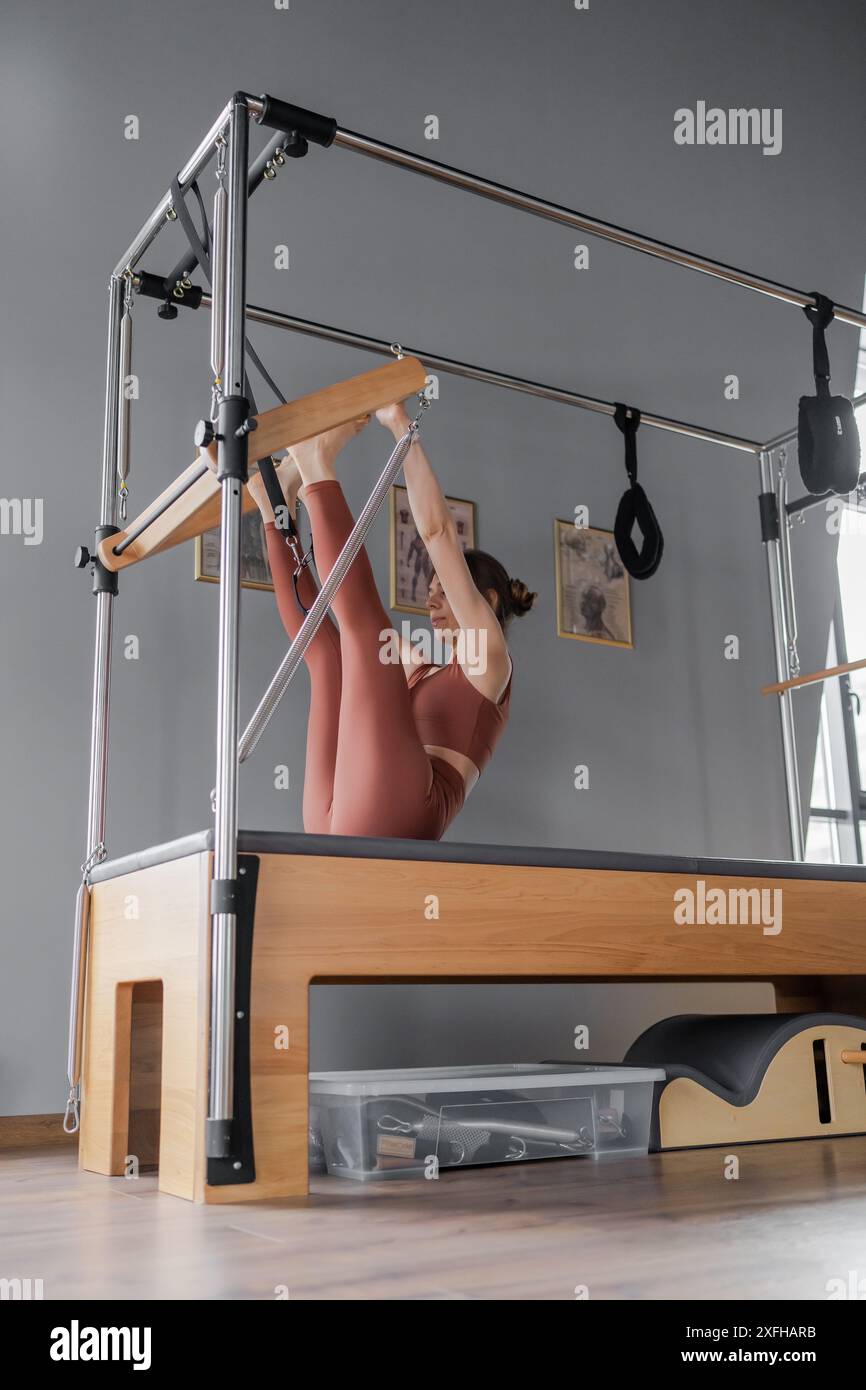 Omsk, Russie - 3 février 2024 : femme faisant des exercices de pilates sur une machine Cadillac à corps équilibré au studio, en se concentrant sur la force et la flexibilité Banque D'Images