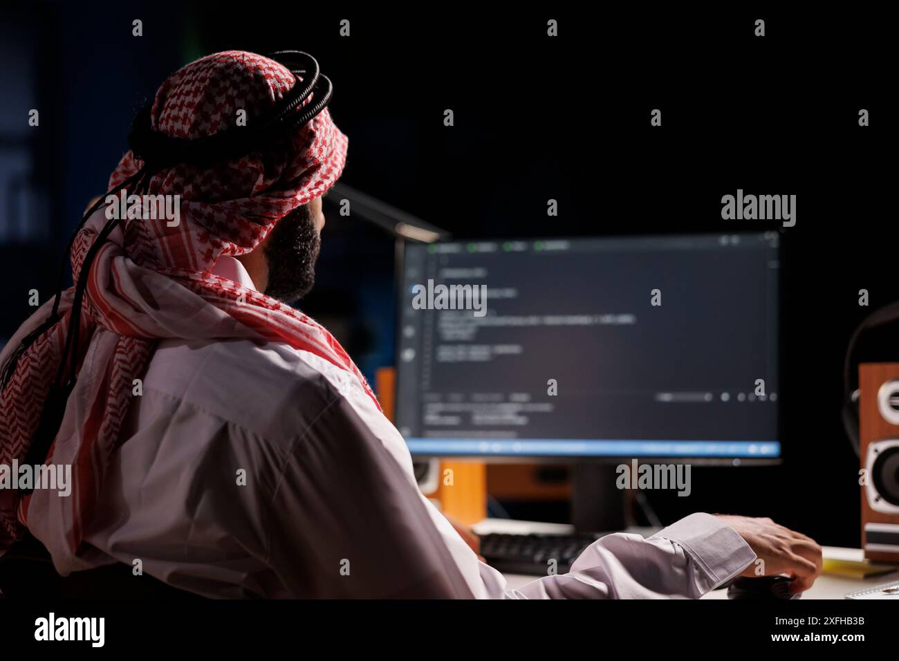 Développeur de logiciels arabe tapant du code et axé sur l'exécution d'algorithmes, mettant en valeur ses compétences en programmation. L'écran de l'ordinateur affiche une interface utilisateur, soulignant l'importance de la sécurité Internet. Banque D'Images