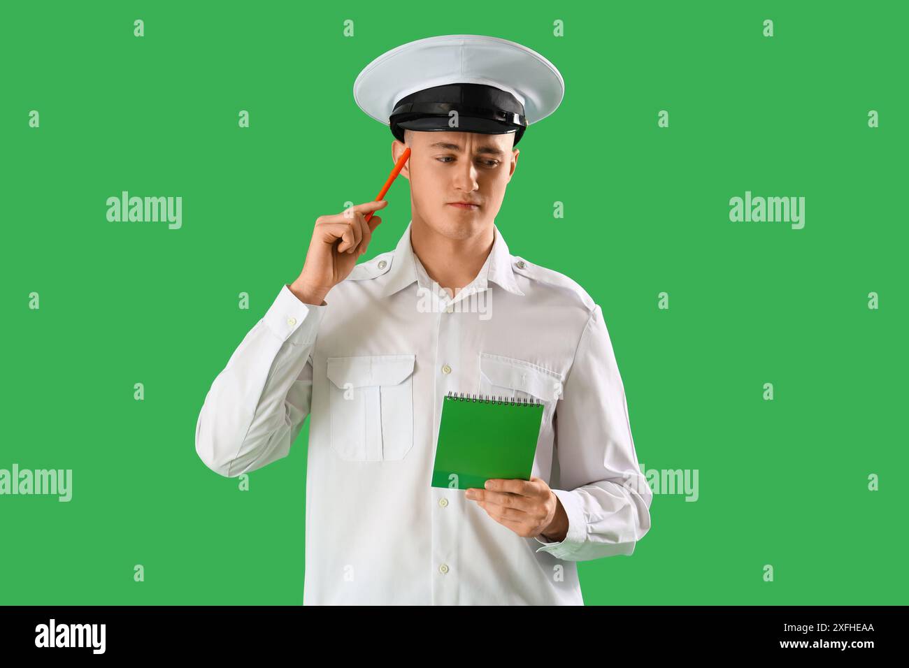 Pilote masculin réfléchi avec cahier sur fond vert. Concept de rappel Banque D'Images