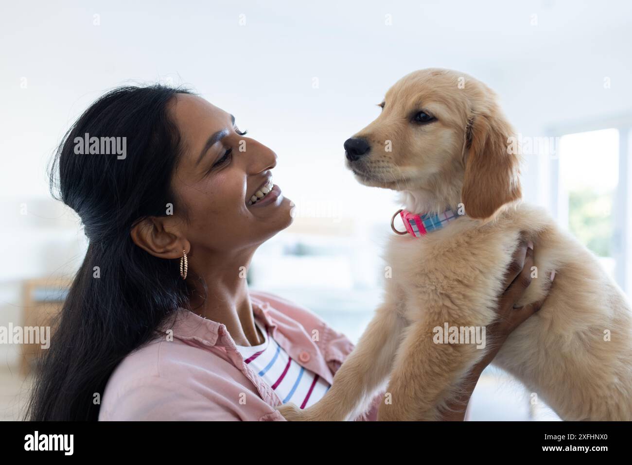 Femme souriante tenant adorable chiot, profitant du temps de qualité à la maison Banque D'Images