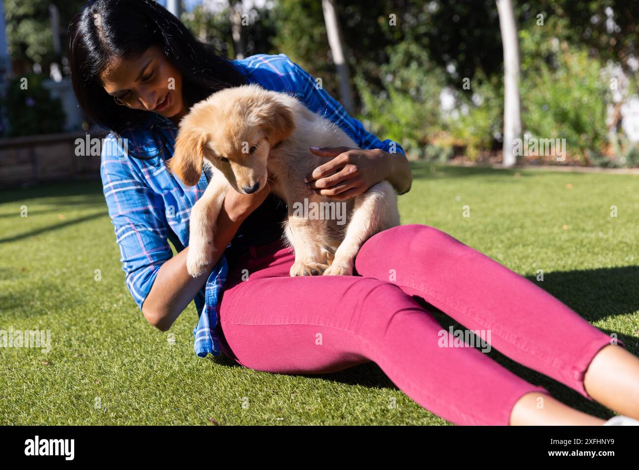 Assis sur l'herbe, femme tenant et jouant avec adorable chiot à l'extérieur Banque D'Images