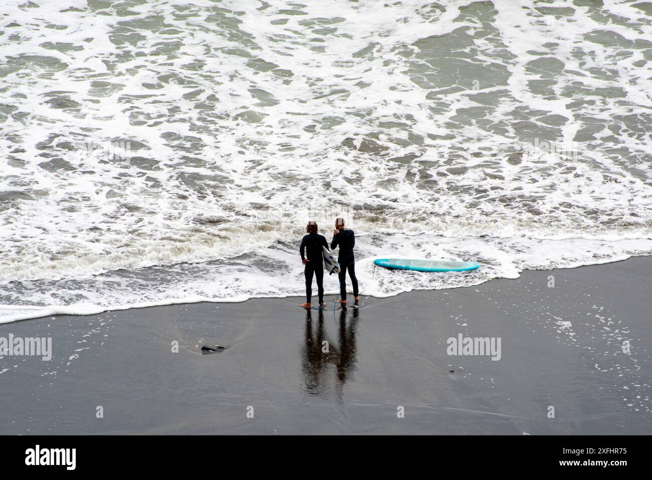 Surfeur à Muriwai Gannet Colony Beach - Nouvelle-Zélande Banque D'Images
