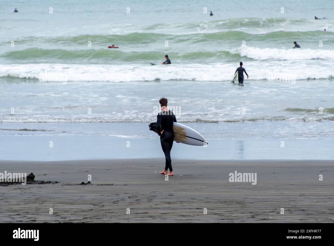 Surfeur à Muriwai Gannet Colony Beach - Nouvelle-Zélande Banque D'Images
