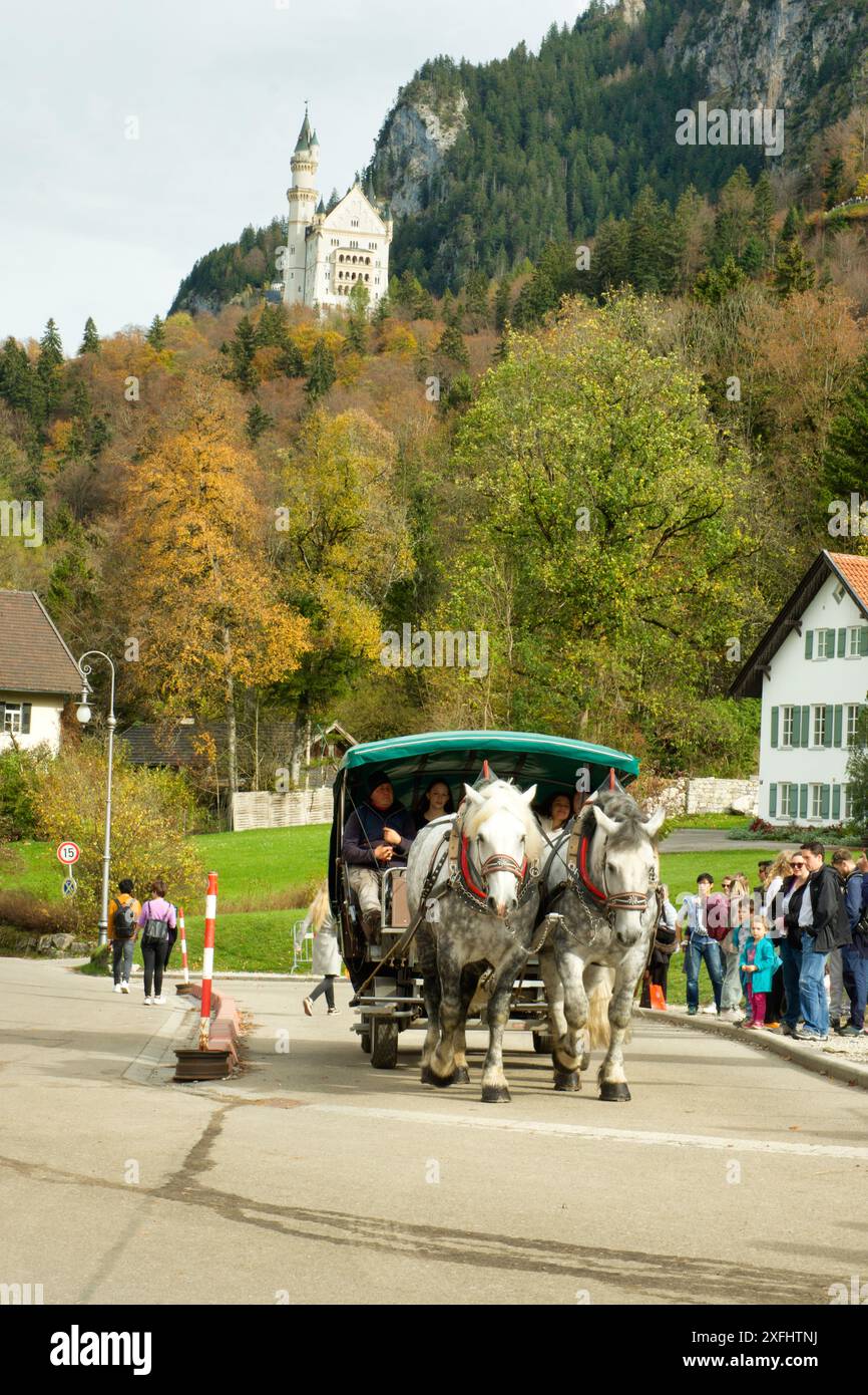 Un cheval et un buggy tirent une calèche dans une rue. Le chariot est vert et présente une bande blanche. Plusieurs personnes sont debout sur le trottoir Banque D'Images