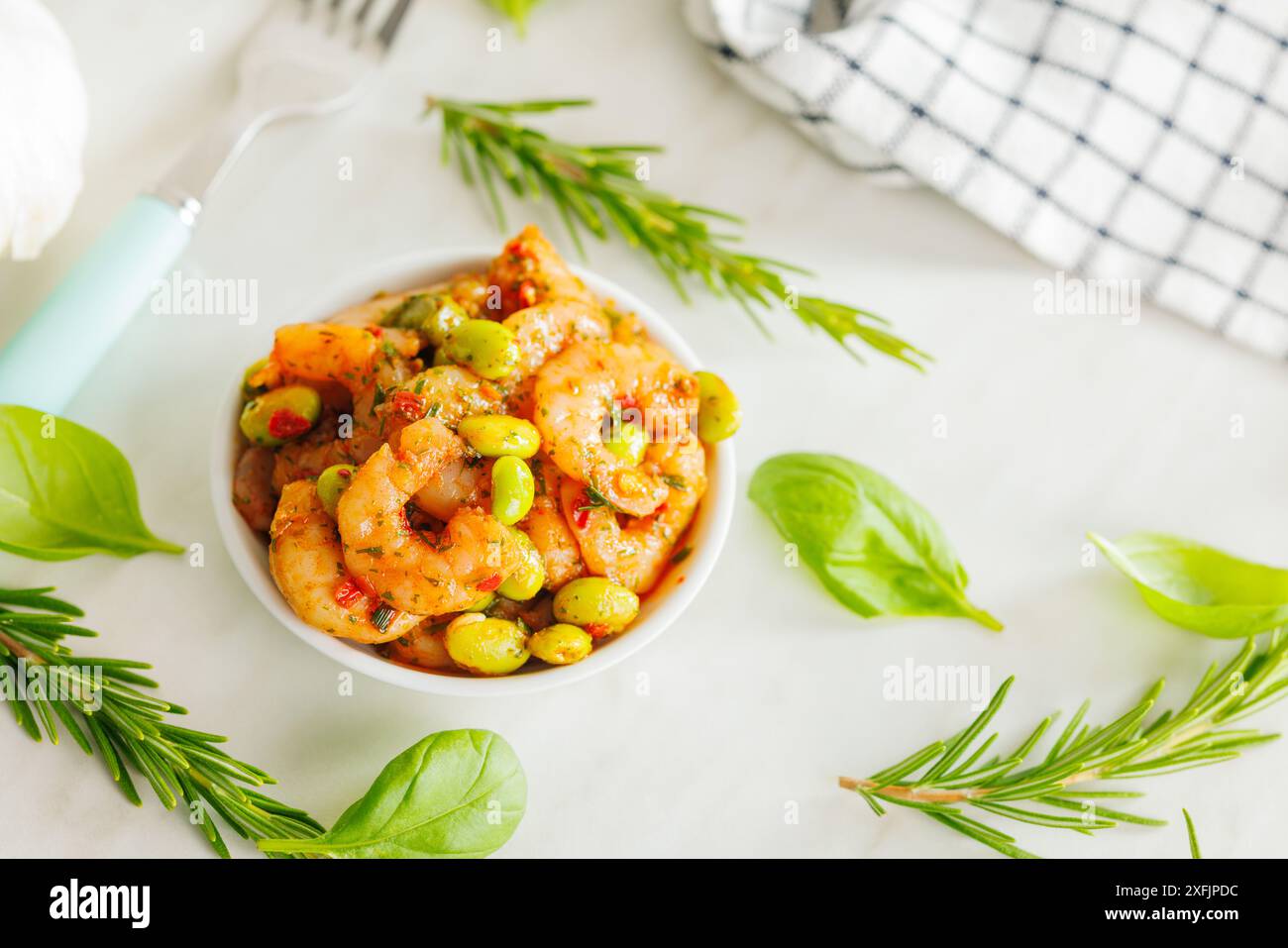 Salade fraîche avec crevettes et soja edamame dans un bol sur une table blanche. Banque D'Images