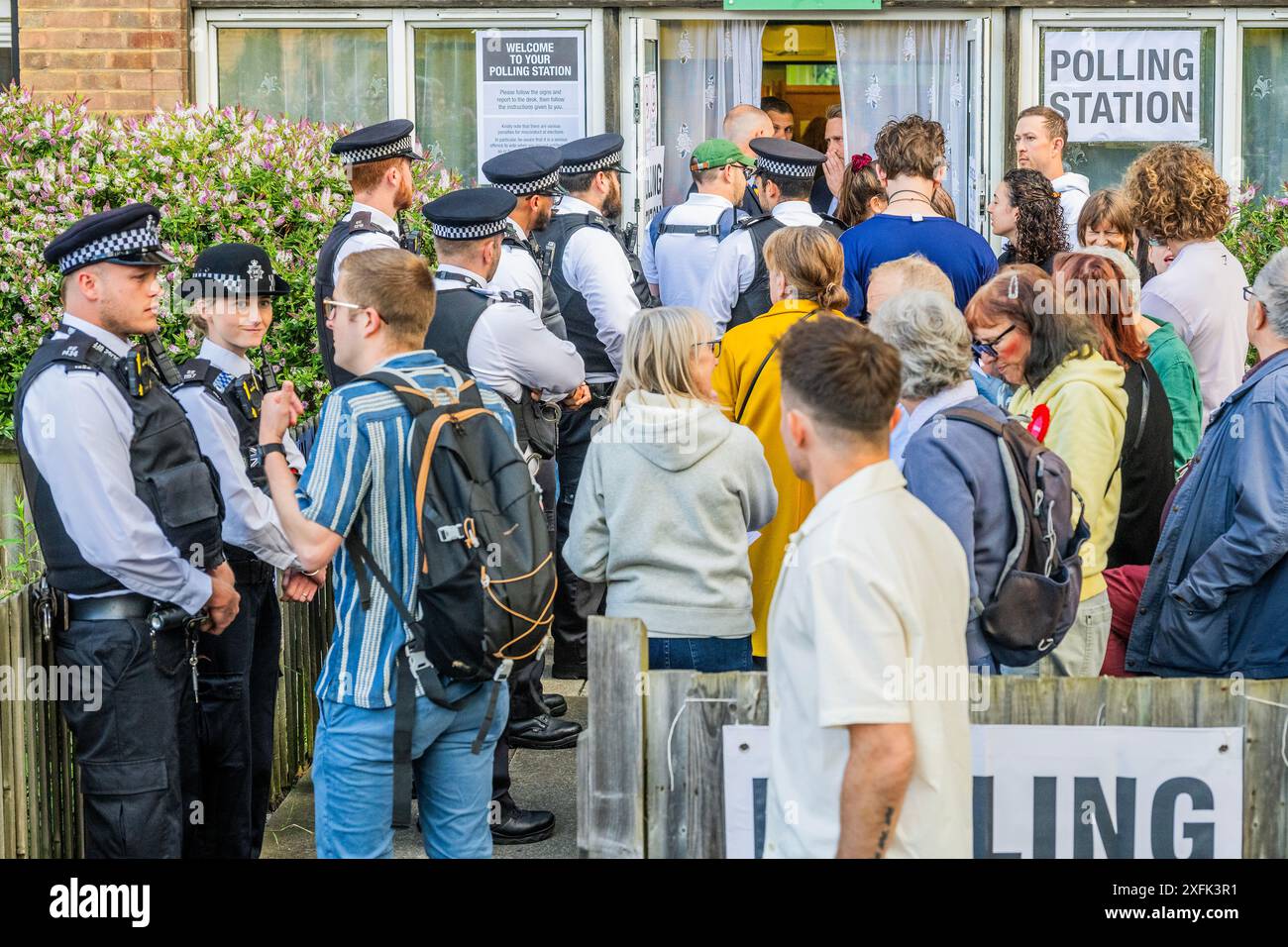 Londres, Royaume-Uni. 4 juillet 2024. La sécurité est étroite avec un grand nombre de policiers debout à l'extérieur avec un groupe d'électeurs en attente - le chef travailliste, Sir Keir Starmer, et sa femme Victoria, votent aux élections générales dans son bureau de vote local dans sa circonscription de Holborn et St Pancras. Crédit : Guy Bell/Alamy Live News Banque D'Images