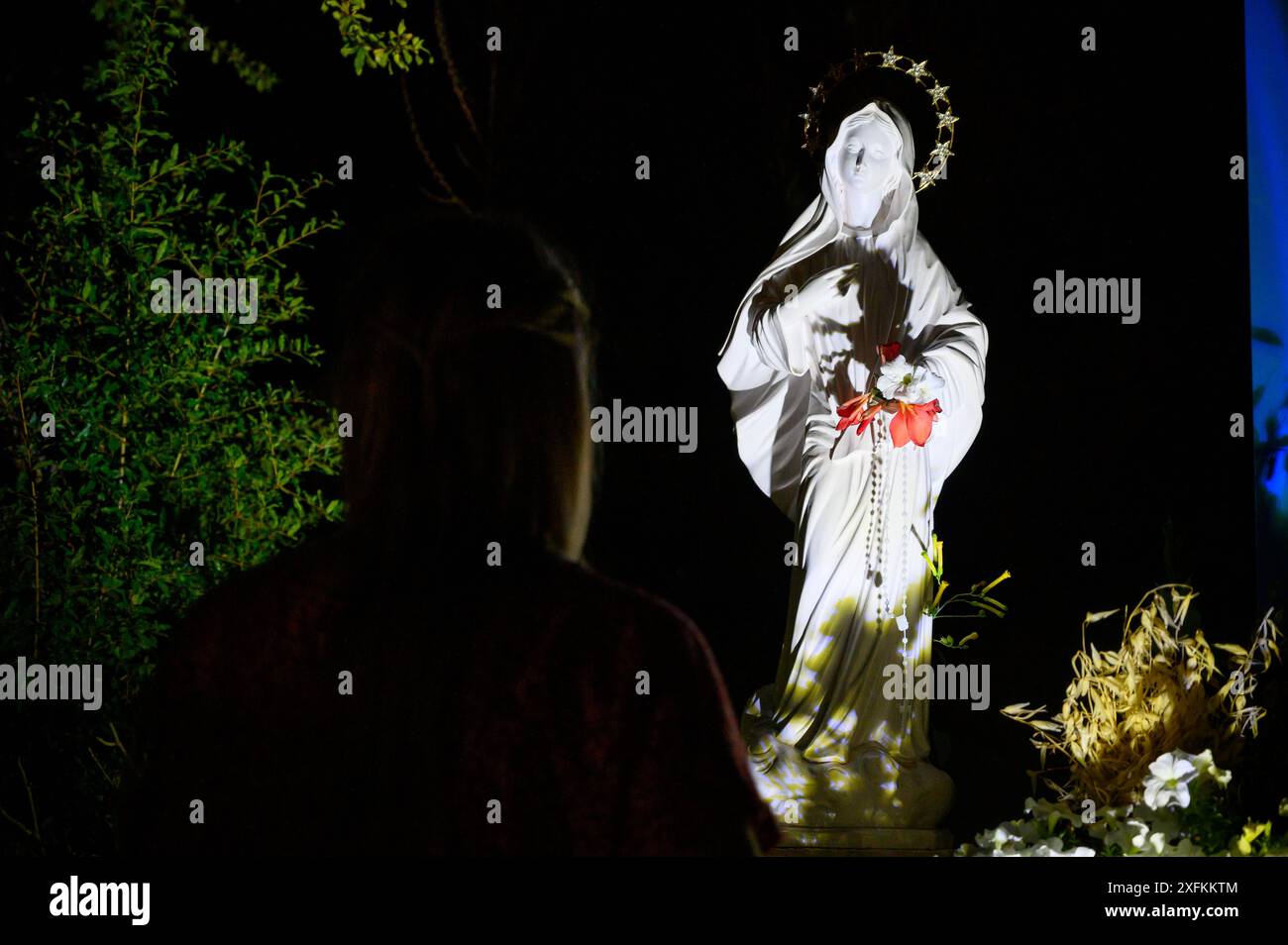 Une femme agenouillée et priant à la Croix bleue la nuit à Medjugorje, Bosnie-Herzégovine. Banque D'Images