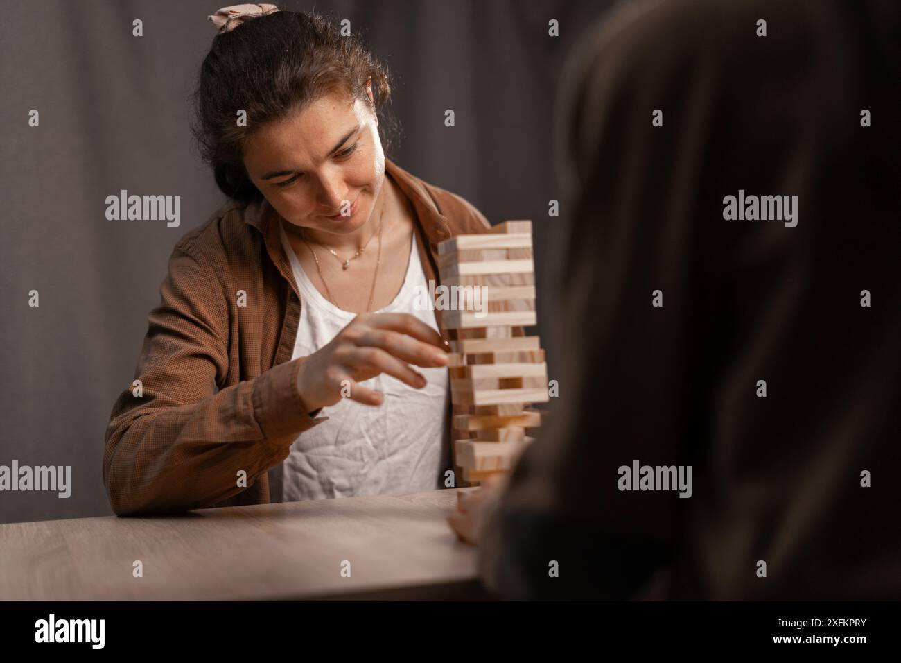 Amis féminins assis et jouant à tour jeu de bloc en bois ensemble à l'intérieur de la maison. Banque D'Images