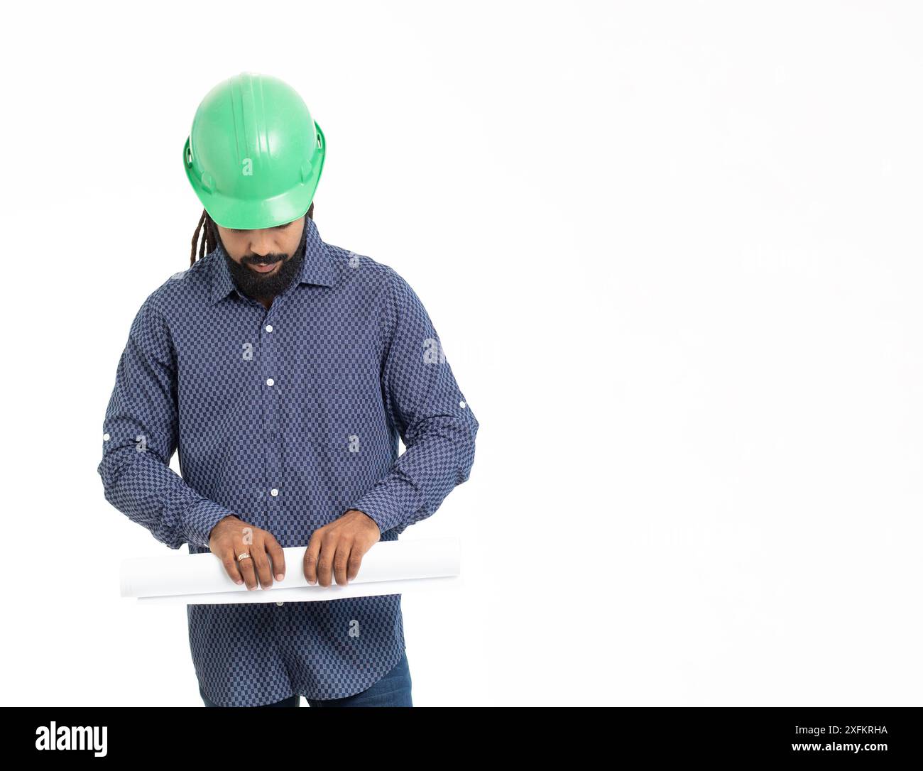 Architecte jeune adulte latin avec HardHat vert , dreadlocks chemise bleue et des plans roulants . caraïbes Banque D'Images