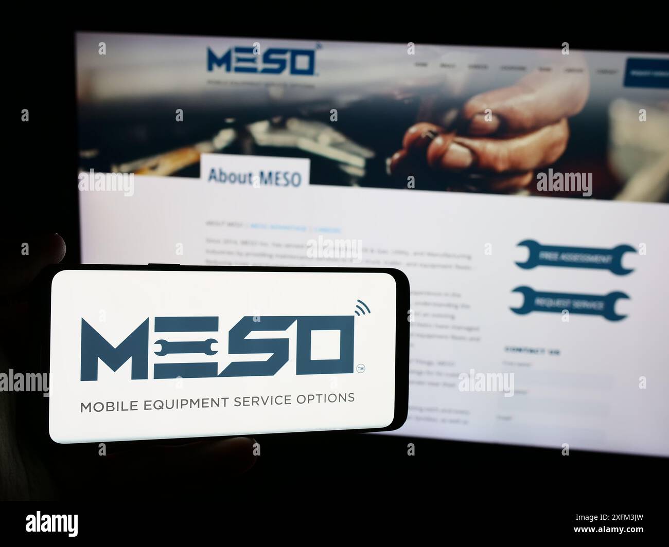 Personne tenant un smartphone avec le logo de la société de services de maintenance américaine MESO Inc en face du site Web. Concentrez-vous sur l'affichage du téléphone. Banque D'Images