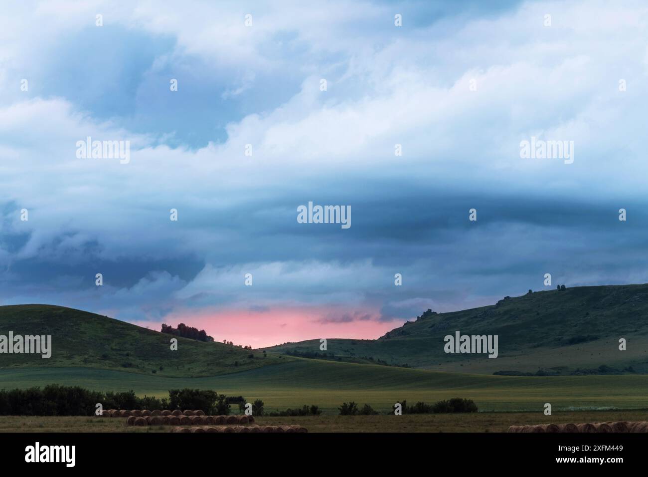 Des prairies verdoyantes et des collines cachant le soleil sous le ciel du soir Banque D'Images