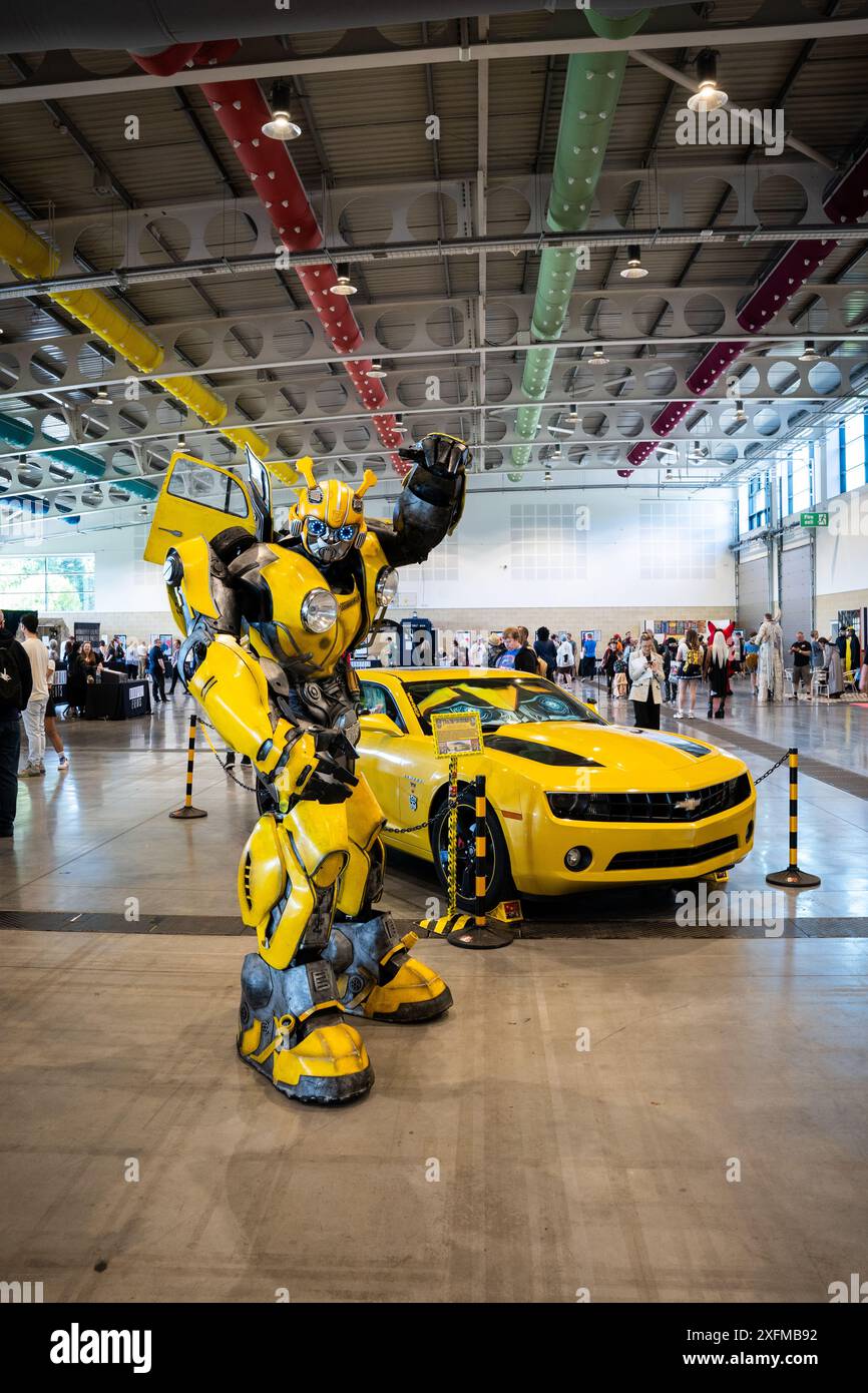 HARROGATE, ROYAUME-UNI - 22 JUIN 2024. Un cosplayer masculin habillé comme le transformer Bumblebee lors d'un événement de comics au Royaume-Uni avec Transformers car Banque D'Images