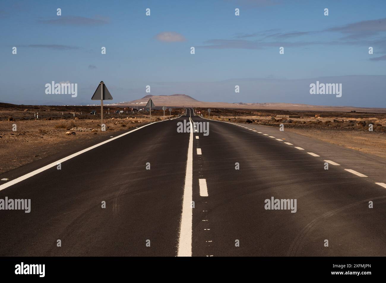 Une longue route vide avec un panneau sur le côté. Le ciel est clair et bleu. La route est vide et il n'y a ni voitures ni personnes sur elle Banque D'Images