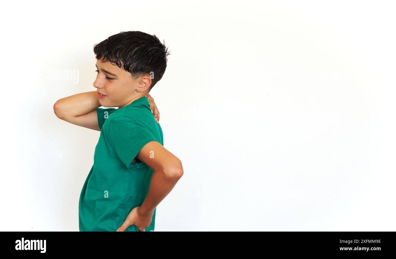 garçon preteen avec des taches de rousseur tenant ses mains derrière son dos dans la douleur et l'inconfort Banque D'Images
