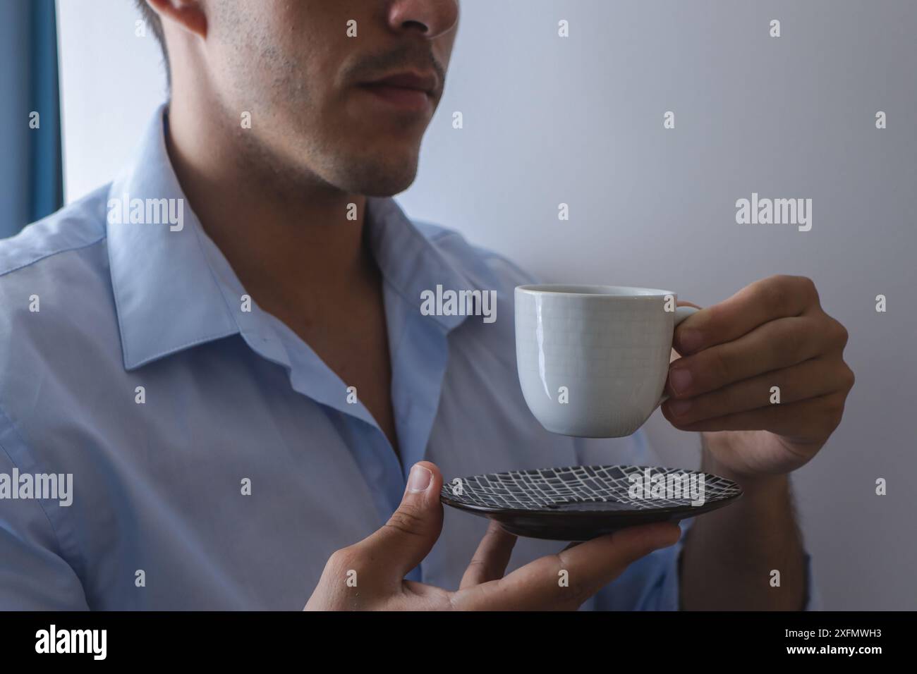 Jeune homme d'affaires assiste à une réunion d'affaires tout en buvant une tasse de café dans une chemise bleue sur une journée de travail normale. Banque D'Images