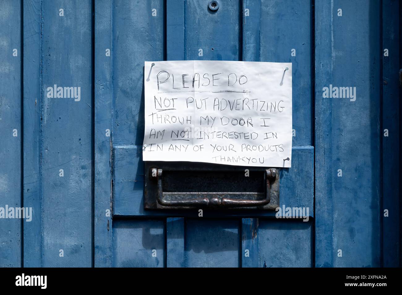 Une note manuscrite amusante collée à une porte d'entrée par le propriétaire de la maison demandant aux gens de ne pas poster de courrier indésirable dans sa boîte aux lettres Banque D'Images