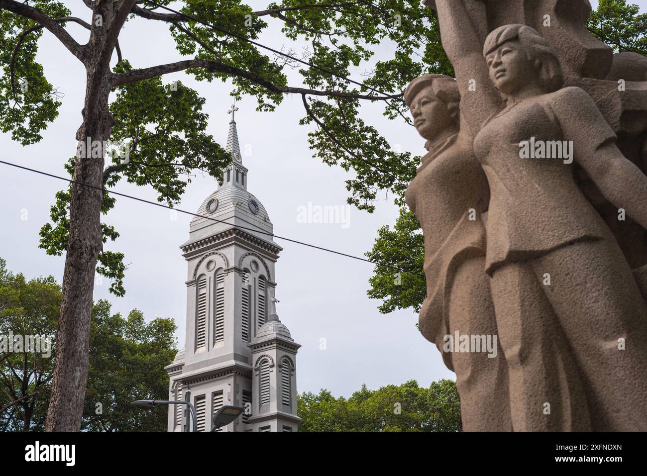 Ho Chi Minh ville, Vietnam - 22 juin 2024 : Eglise de Jeanne d'Arc avec une sculpture dans le style du réalisme socialiste dans le parc Công viên Văn Lang. Banque D'Images
