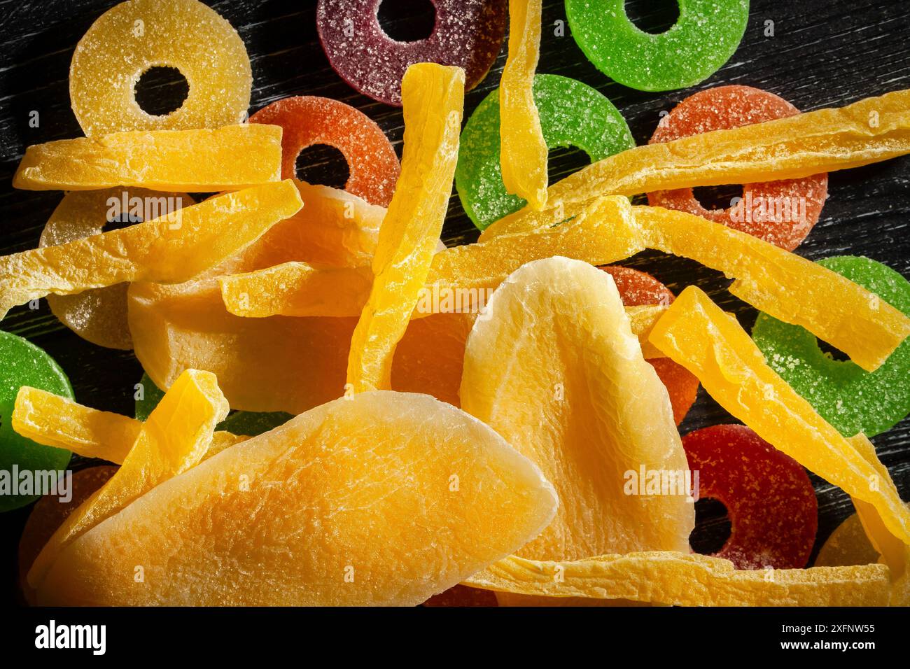 bonbons au cantaloup à la mangue séchée sur fond de bois noir vue de dessus Banque D'Images